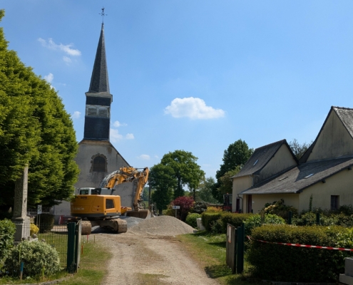 Photographie montrant une pelleteuse en action devant l'église paroissiale de Saint-Sulpice-la-Forêt